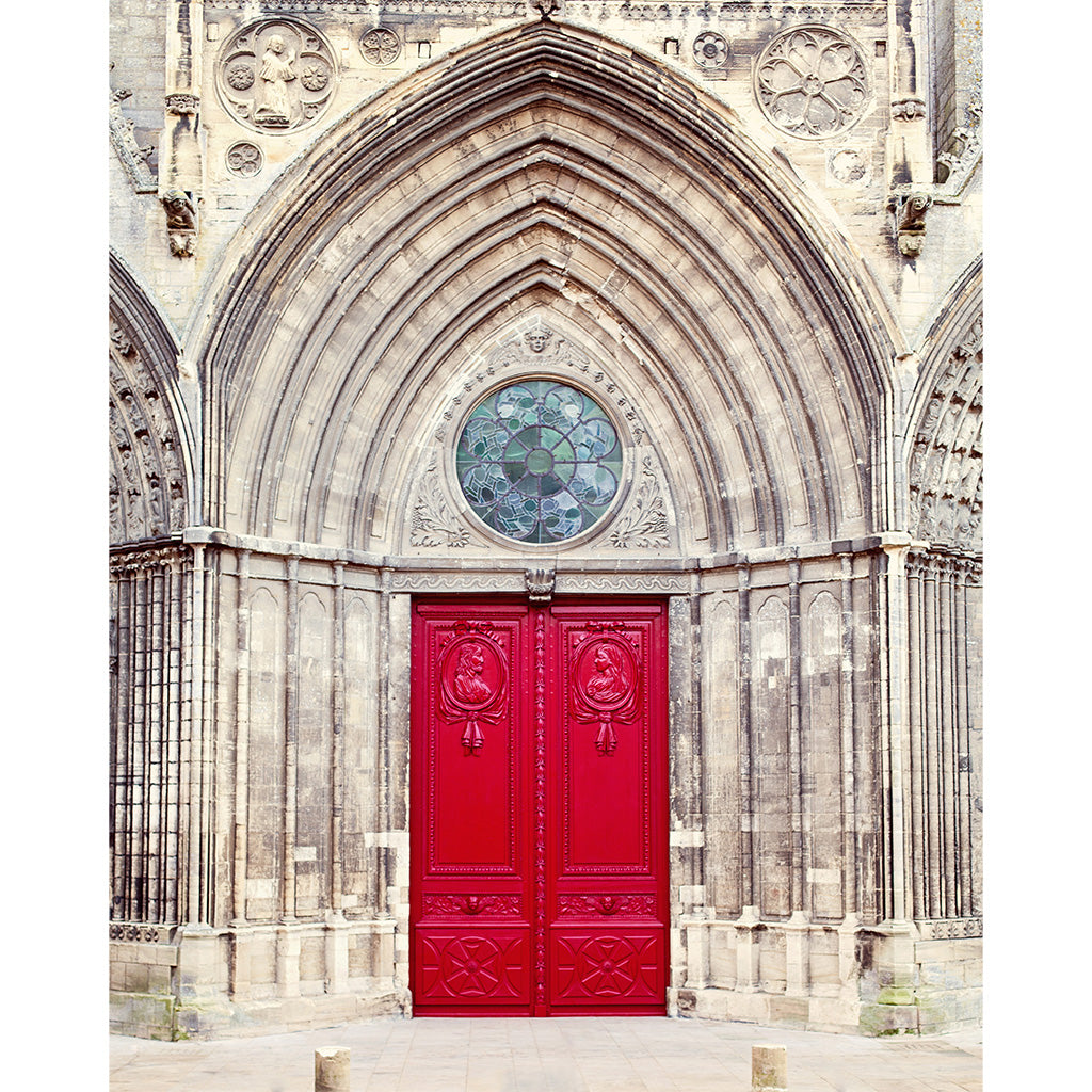 A pair of ornate bright red double doors set within a large stone Gothic cathedral facade, featuring a circular stained-glass window above the entrance.
